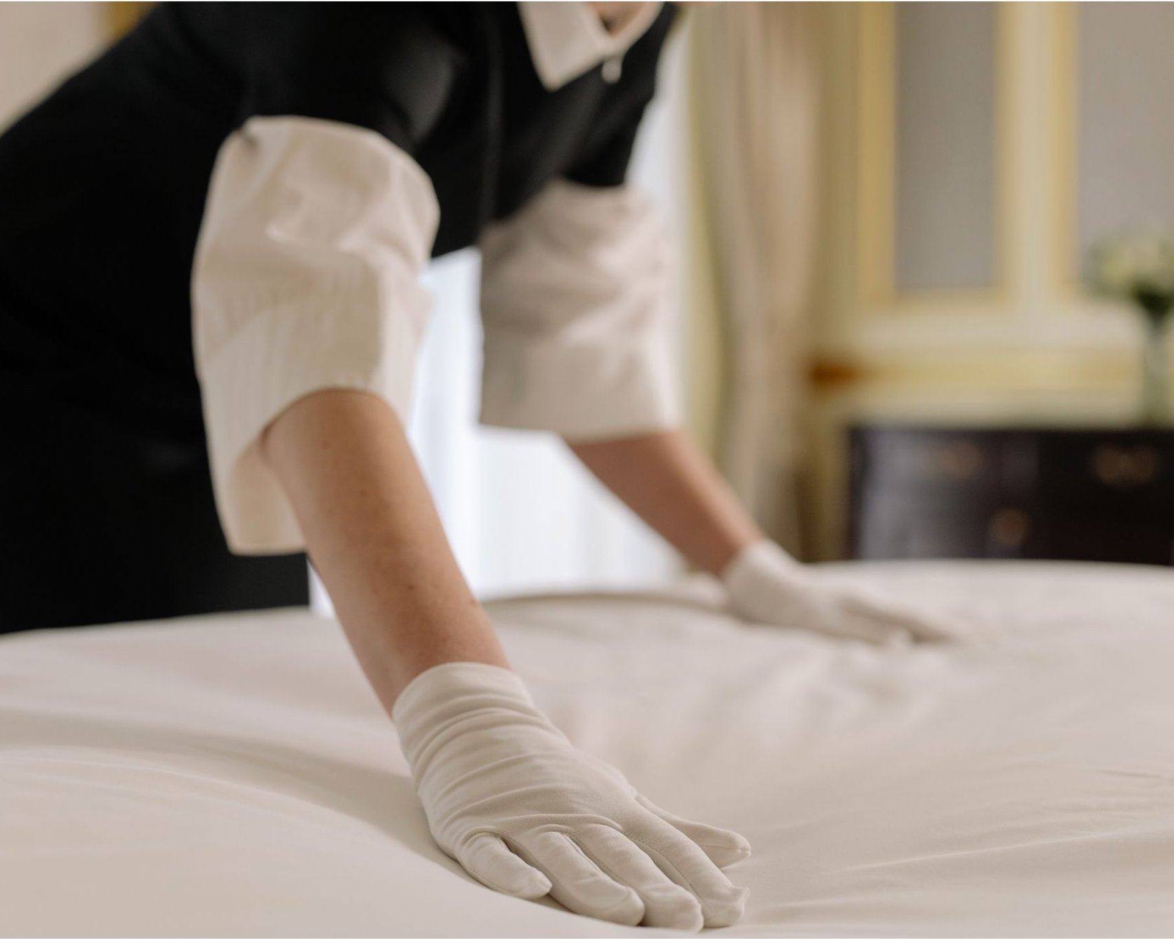 Hotel housekeeping staff making a bed with fresh white linens in a guest room