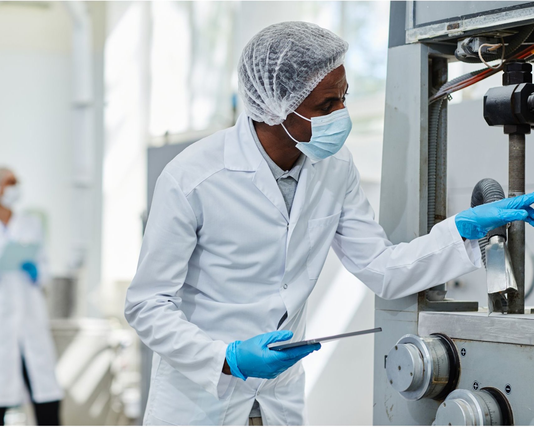 Commercial staff in protective gear inspecting equipment with a tablet